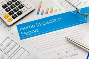 Home inspection report document with calculator, pen, and glasses on a desk