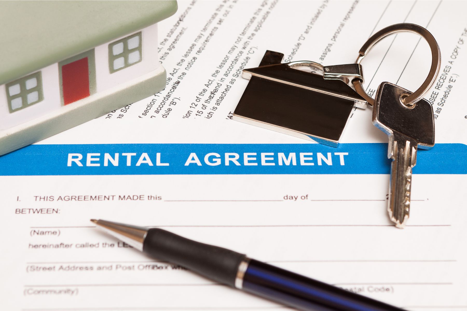 Rental agreement document with house keys, a pen, and a model home, representing an Indiana rent-back agreement after closing