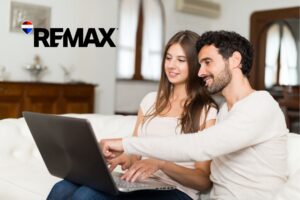 Two people sitting on a couch reviewing a home on a laptop together, researching buying a house sight unseen in Indiana