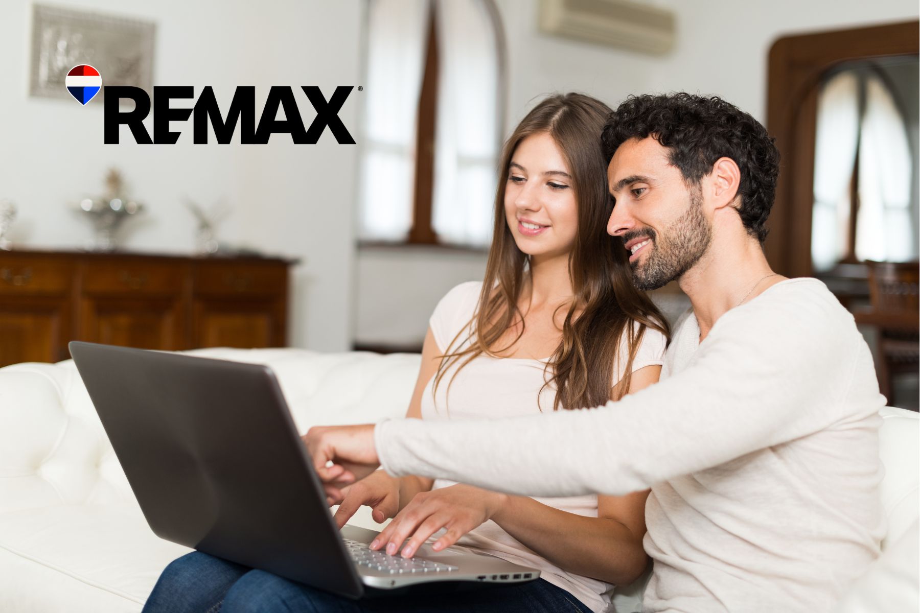Two people sitting on a couch reviewing a home on a laptop together, researching buying a house sight unseen in Indiana