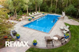 Aerial view of a large inground swimming pool with a slide and stamped concrete patio in a fenced Indiana backyard